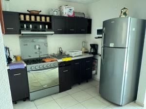 uma cozinha com um frigorífico de aço inoxidável e armários pretos em Acapulco Marina Diamante em Acapulco