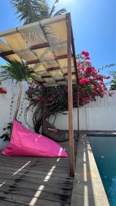 einem rosa Regenschirm auf einem Deck neben einem Pool in der Unterkunft Villa Luna Sunset Beach in Gili Trawangan