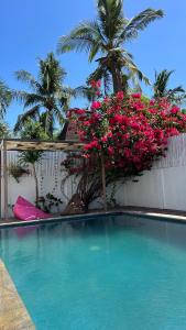 een zwembad met roze bloemen op een hek bij Villa Luna Sunset Beach in Gili Trawangan