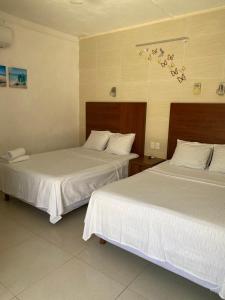 two beds with white sheets in a hotel room at Hotel San Julio in Celestún