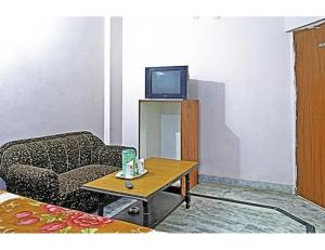ein Wohnzimmer mit einem Sofa und einem Tisch mit einem TV in der Unterkunft Viren Plaza, Agra in Agra