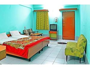 a bedroom with a bed and a chair and a tv at Viren Plaza, Agra in Agra