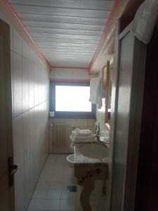 ein kleines Bad mit einem Waschbecken und einem Fenster in der Unterkunft Oberthaler Hotel in Sappada