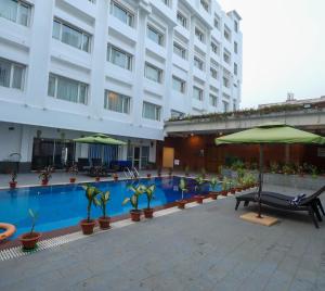 un hotel con piscina con ombrelloni e piante di IRA By Orchid Bhubaneswar a Bhubaneshwar