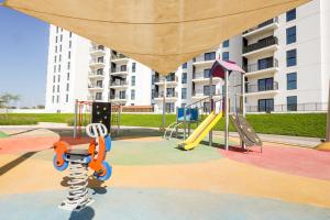 um parque infantil com um escorrega e um equipamento de brincar em One Bedroom Hosted By Voyage em Abu Dhabi