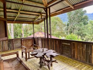 a screened in porch with a table and a bench at Batu Kapal Lodge in Bukit Lawang