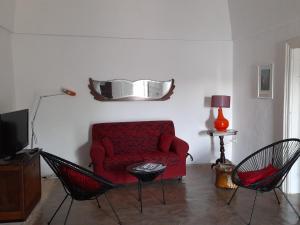 een woonkamer met een rode bank en 2 stoelen bij Villa Ottocento Molillo in Ostuni