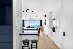 a kitchen with two bar stools and a kitchen with a view at 9 La Mer, 5 Belmore Tce - Ultimate Beachside Living in Sunshine Beach +21 photos