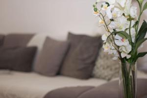 a vase filled with white flowers in front of a couch at Spacious 2 bedroom apartment in Central Oxford in Oxford