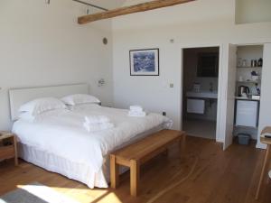 a bedroom with a large white bed and a kitchen at The Suites at Pannells Ash in Castle Hedingham