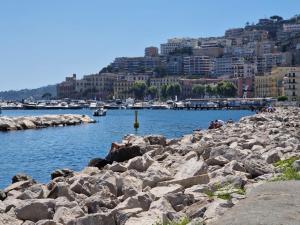 un grupo de personas sentadas en rocas cerca de un cuerpo de agua en Suites Caracciolo, en Nápoles
