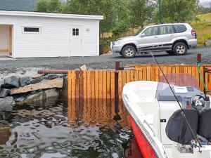 un bateau dans l'eau à côté d'une clôture et d'une voiture dans l'établissement 8 person holiday home in Svelgen, à Svelgen