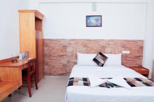 1 dormitorio con 2 camas y escritorio de madera en A V Residency, en Kochi