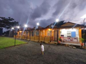Mandav Hills Resort & Film City في Māndu: صبي صغير يقف أمام منزل في الليل