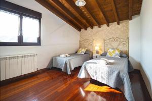 sypialnia z 2 łóżkami w pokoju z drewnianą podłogą w obiekcie Casa Azul De Perlleces w mieście Cangas de Onís