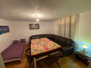 ein Wohnzimmer mit einem Tisch und einem Ledersofa in der Unterkunft Casa din deal in Muşca