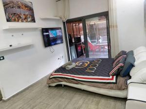 1 dormitorio con 1 cama en una habitación con TV en Luxury Jacuzzi Near Beach, APT with 80sq garden, en Bat Yam