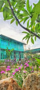ein blaues Gebäude mit rosa Blumen davor in der Unterkunft Mina Café & Stay in Quan Lạn-Insel