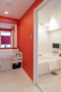 ein Badezimmer mit roten Wänden, einer Badewanne und einem Waschbecken in der Unterkunft hotel VR osaka in Osaka