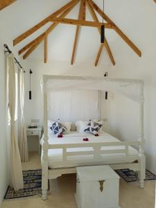 1 dormitorio con 1 cama blanca con dosel blanco en Sonrisa Villas, en Diani Beach