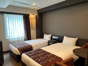 大阪市にあるhotel VR osakaのベッド2台とテーブルが備わるホテルルームです。