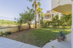 un patio trasero con palmeras y una casa en Residence w Terrace Garden 15 min to Belek Beach, en Belek