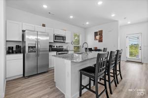 a kitchen with a refrigerator and a counter with chairs at Pacific Palace-NEW 2bed 2 5bath Home in Centerton in Bentonville