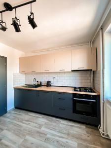 a kitchen with white cabinets and a black stove at Central Station Two-Bedroom Family Apartment in Timişoara