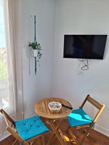 梅里尼亞克的住宿－La Maison Partagée d'Arlac，一间配备有桌子和两把椅子及一台电视的房间