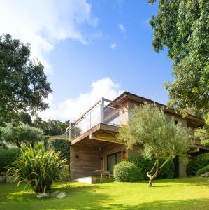 une maison avec un balcon en verre au-dessus d'une cour dans l'établissement Hôtel Version Maquis Santa Manza, à Bonifacio