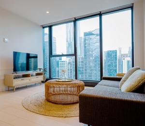 a living room with a couch and a large window at Cozy & spacious 2B2B APT in CBD in Melbourne
