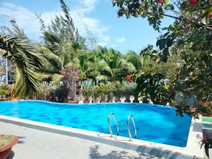 a swimming pool in a resort with palm trees at Phuc Thuan Hotel - Ninh Thuan in Phan Rang