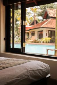 Le Baan Thai Boutique Villa في شيانغ ماي: غرفة نوم مع نافذة كبيرة تطل على حمام سباحة