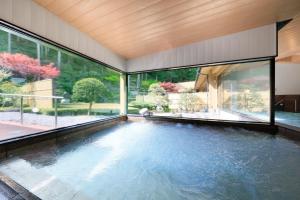 Komaba的住宿－湯元ホテル阿智川，一座带大窗户的房屋内的游泳池