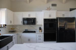 a kitchen with white cabinets and black appliances at Casa Mariposa - A Foothill Retreat near Yosemite in Mariposa