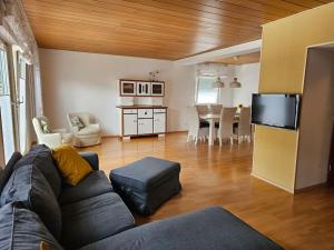 a living room with a couch and a table and a kitchen at Große Ferienwohnung am Waldrand in Schönau