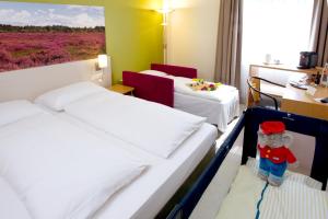 una habitación de hotel con 3 camas y un osito de peluche en Anders Hotel Walsrode, en Walsrode