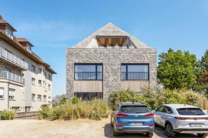 two cars parked in front of a house at Luxe strandappartement met zonneterras & parking in Koksijde