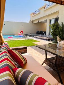 a patio with a couch and a table and a pool at شالية راقي بمسبح وجلسات خارجية in ‘Ilb