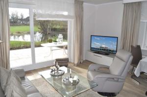 ein Wohnzimmer mit einem Sofa, einem TV und einem Tisch in der Unterkunft myOSTSEE Dream Ferienwohnung in Niendorf