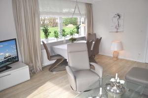 ein Wohnzimmer mit einem Tisch, Stühlen und einem TV in der Unterkunft myOSTSEE Dream Ferienwohnung in Niendorf