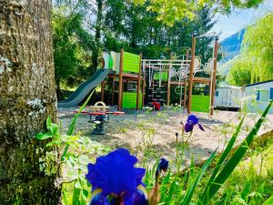 um parque com parque infantil com escorrega e flores azuis em Le Vallon em Ispagnac