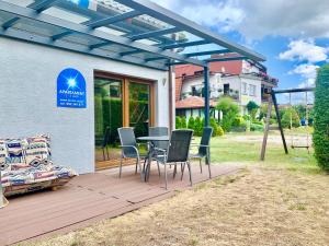 a patio with a table and chairs in front of a house at Fonica - Domek Apartament in Łeba +3 photos
