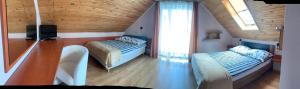 a attic room with two beds and a television at Fonica - Domek Apartament in Łeba