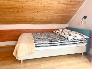a bed in a room with a wooden ceiling at Fonica - Domek Apartament in Łeba