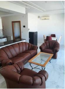 een woonkamer met 2 leren banken en een salontafel bij Panamera vue mer 180 degré in Sousse