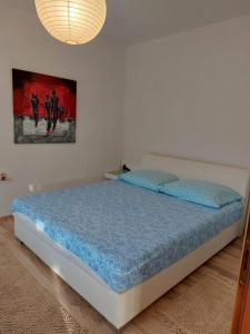 a bedroom with a bed with blue sheets and a painting at Apartmani Neda in Čitluk