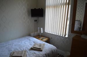 a bedroom with a bed and a television and a window at The Rutlands in Blackpool