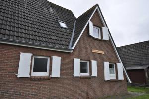 a brick house with white windows and a roof at Nr 31 - Ferienhaus Am Yachthafen in Carolinensiel