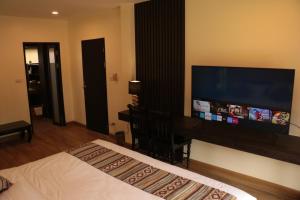 a bedroom with a bed and a large flat screen tv at Le Baan Thai Boutique Villa in Chiang Mai
